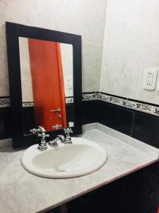 a bathroom sink with a red door and a mirror at Departamento-Casa-Marcos in La Plata