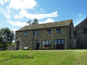 a stone house with a grass field in front of it at Pott Hall in Masham