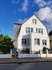 ein weißes Haus mit einem weißen Zaun in der Unterkunft Haus MeerZeit in Cuxhaven