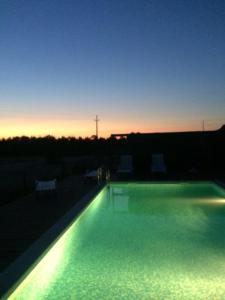 a large swimming pool with lights in front of a sunset at Monte Loureiro-caveira in Melides