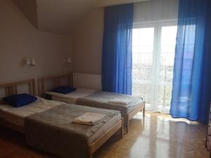 a room with two beds and a window with blue curtains at Zajazd Bachus in Czarnocin