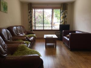 a living room with leather couches and a coffee table at Four-Bedroom House - Stratherrick Free Parking in Inverness