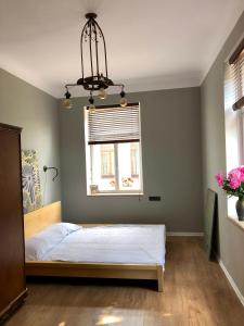 a bedroom with a bed and a window and a chandelier at Bohemian apartment in the heart of old Ventspils city in Ventspils