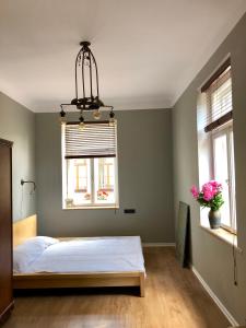 a bedroom with a bed and two windows at Bohemian apartment in the heart of old Ventspils city in Ventspils