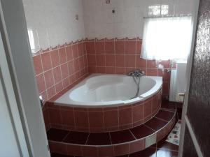 a red tiled tub in a bathroom with a window at Rózsa apartman in Lenti +4 photos