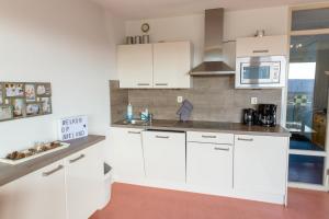 a kitchen with white cabinets and a microwave at Dünenglück in Buren