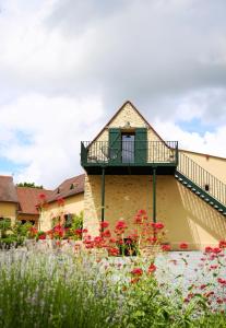 a house with a balcony and flowers in the yard at equihome in Écommoy