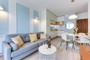 GRANO APARTMENTS Gdańsk Nowa Motława SPA & Wellness في غدانسك: غرفة معيشة مع أريكة وطاولة