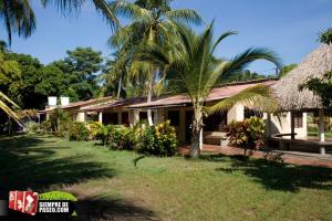 a house with a palm tree in front of a yard at Hostal Roldan in Coveñas