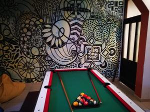 a pool table in front of a wall with a mural at Balkaneros Hostel in Mostar