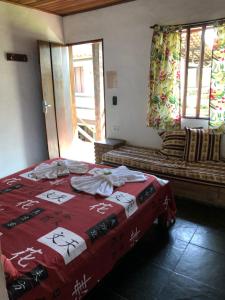 a bedroom with a bed with a red blanket at Pousada Conde do Mar in Ilhabela