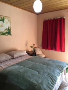 a bedroom with a large bed with a red curtain at Cantinho da Paz in São Pedro da Serra