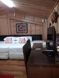1 dormitorio con cama con almohadas rosas y escritorio en 奮起湖車站 揚揚民宿, en Fenchihu
