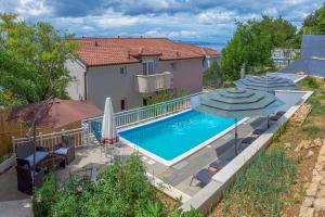 a swimming pool with umbrellas next to a house at Vigo Apartments Croatia in Celina