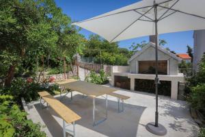 a picnic table with an umbrella and a grill at Apartment Vitaic in Supetar