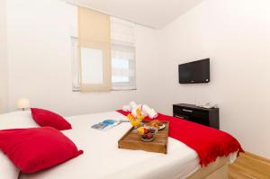 ein Bett mit roten Kissen und ein Tablett mit Blumen drauf in der Unterkunft Apartments Maja in Okrug Donji