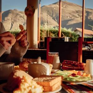 una mesa llena de comida con una montaña en el fondo en Casona Plaza Ecolodge Colca, en Yanque