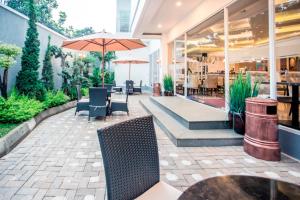 a patio with chairs and tables and an umbrella at Savero Hotel Depok in Depok