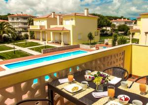 a balcony with a table and a swimming pool at Praia Del Rei Pool View in Casal da Lagoa Seca