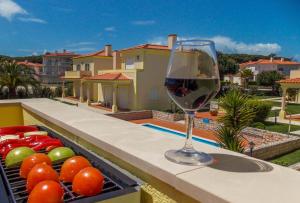 una copa de vino en el balcón con un bol de fruta en Praia Del Rey Pool View ByThe Sea, en Casal da Lagoa Seca