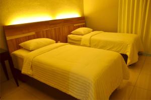 two beds in a hotel room with white sheets at MTC Mega Mas Apartment in Manado