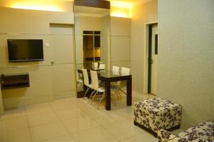 une salle à manger avec une table, des chaises et une télévision dans l'établissement MTC Mega Mas Apartment, à Manado