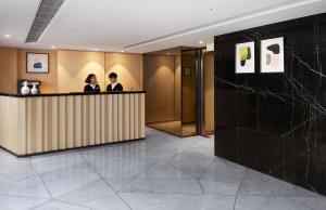 due persone in piedi a un bancone in una hall di The OTTO Hotel a Hong Kong