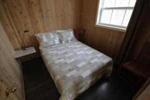 a small bed in a room with a window at Tadou-Shack in Tadoussac