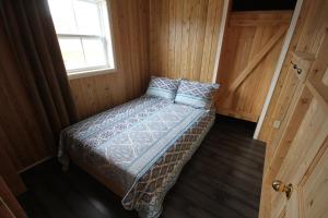 uma cama num pequeno quarto com uma janela em Tadou-Shack em Tadoussac