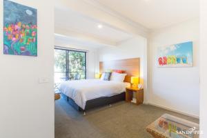 a bedroom with a bed and a painting on the wall at Sandpiper Motel Apollo Bay in Apollo Bay