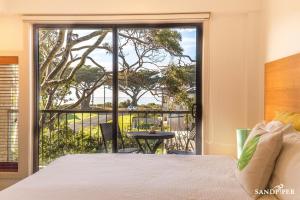 a bedroom with a bed and a view of a balcony at Sandpiper Motel Apollo Bay in Apollo Bay