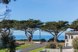 Sandpiper Motel Apollo Bay في خليج أبولو: a car driving down a street with trees and the ocean