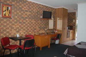Habitación con pared de ladrillo, mesa y sillas. en Horsham Mid City Court Motel, en Horsham