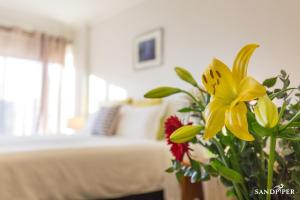 a vase of flowers in a room with a bed at Sandpiper Motel Apollo Bay in Apollo Bay