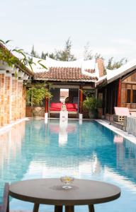 a pool with a table in front of a house at Villa Louise Hue Beach Boutique Hotel in Hue