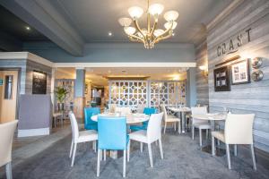 a dining room with tables and chairs and a chandelier at The Glendower Hotel in Lytham St Annes