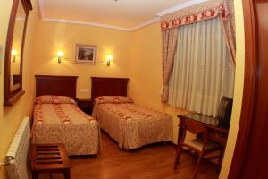 a hotel room with two beds and a desk at Hostal Torres in San Leonardo de Yagüe