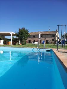 - une piscine d'eau bleue en face d'une maison dans l'établissement Il Gallo Del Vicino, à Monte Urano