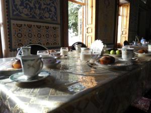 una mesa con tazas y platos de comida. en Hotel Mosque Baland, en Bukhara