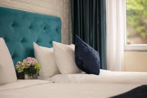 a bed with a blue headboard and a vase of flowers at Catba Palace Hotel in Cat Ba