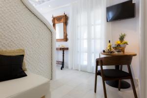 Cette chambre comprend une table avec une chaise et un miroir. dans l'établissement Naxian Riviera Exclusive Seafront Suites, Junior Suite, à Ágios Prokópios