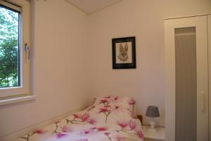 a bedroom with a bed with pink sheets and a window at t'Bakkersboschje nummer 11 in Putten