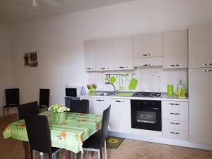 a kitchen with white cabinets and a table with chairs at Casa Gavi in Tre Fontane