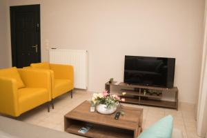 a living room with two yellow chairs and a television at Mary's House in Lefkada Town
