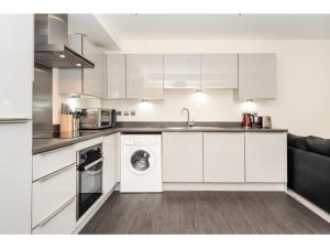 uma cozinha com armários brancos e uma máquina de lavar e secar roupa em Stylish Flat Near the City Centre - Pass the Keys em York