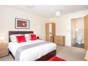 una camera da letto con un grande letto con cuscini rossi di Stylish Flat Near the City Centre - Pass the Keys a York