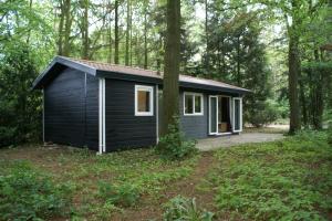 una pequeña casa negra en el bosque en t'Bakkersboschje nummer 11, en Putten