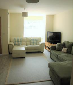 a living room with two couches and a flat screen tv at Bright modern house beside Snowdonia in Llanfairfechan