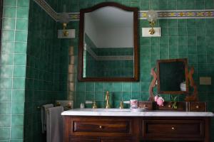 a green tiled bathroom with a sink and a mirror at Torre Colombaia in Salsomaggiore Terme