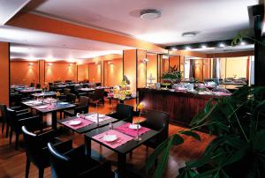 un restaurante con mesas y sillas y un bar en Hotel La Fenice, en Belpasso